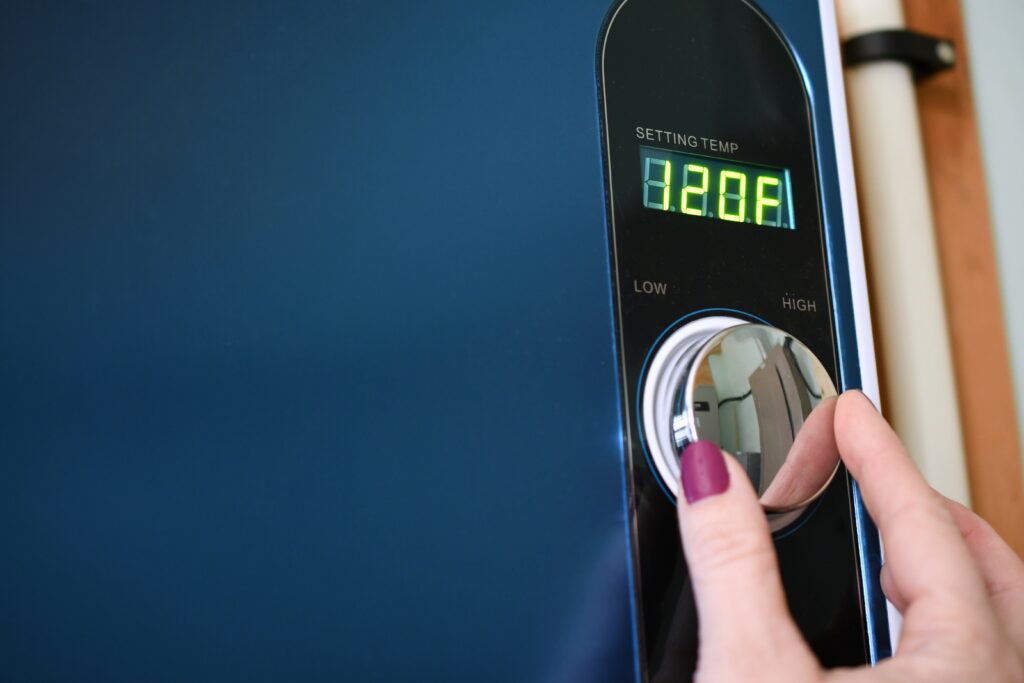 Photo of a woman's hand adjusting the temperature on a tankless water heater.