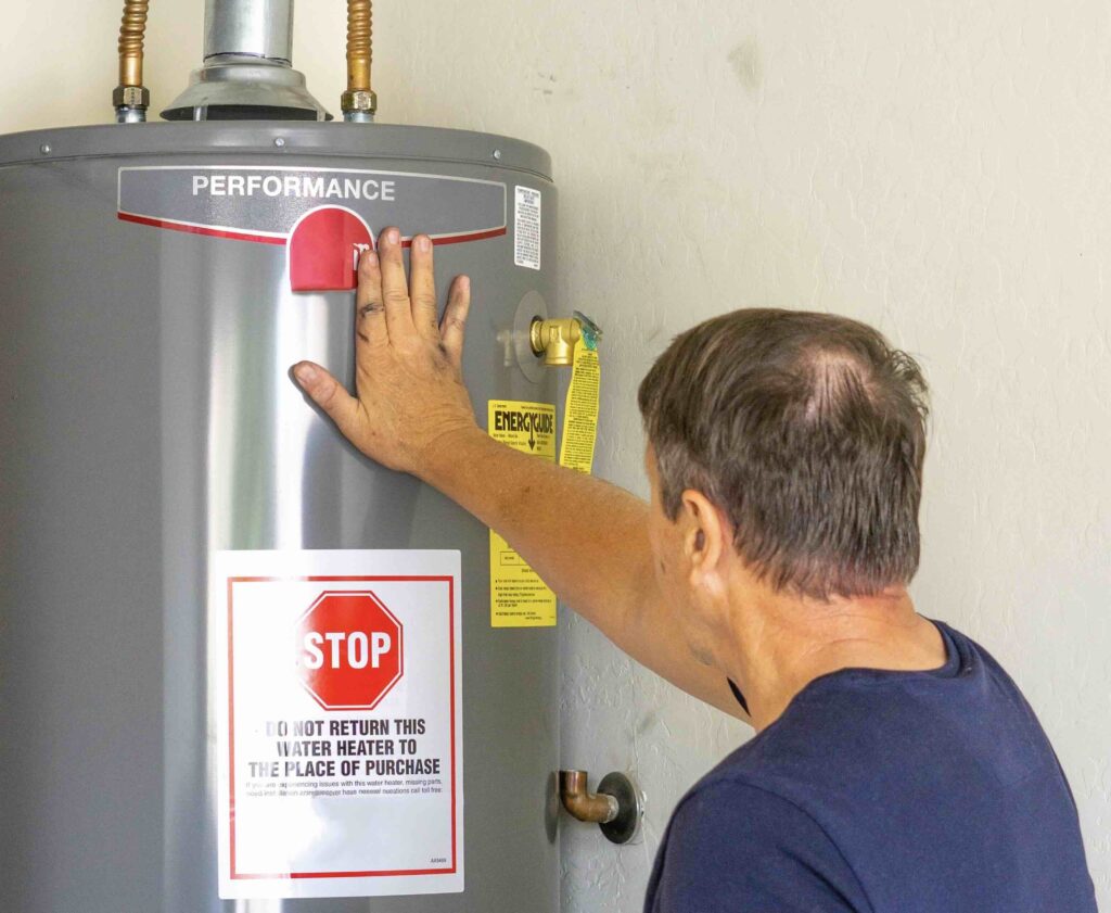 Photo of a man working on a traditional water heater.
